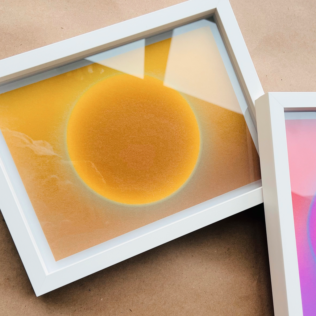 A framed product shot of the Solar N°1 art print, featuring a soft golden sun with a luminous gradient against a light-textured off-white background.